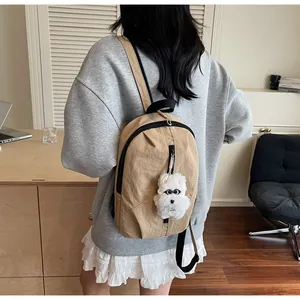 Dettaglio mini zaino in nylon marrone chiaro con un ciondolo a forma di cane di peluche