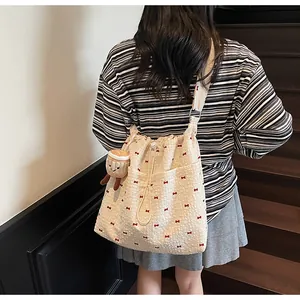 Detailed view of beige canvas bucket bag with red bows and plush toast charm