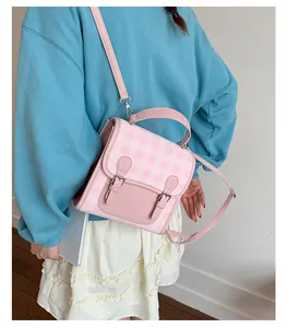 Pink checkered mini backpack with leather handles and straps shown on a model