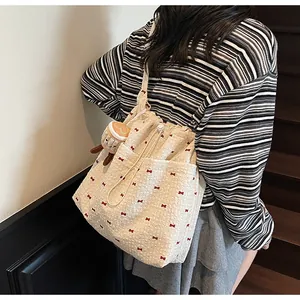 Close-up of cream mesh shoulder bag with red bows and cute plush toast keychain