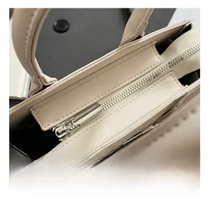 Detail of silver metallic zipper and grainy leather texture on a beige saddle bag