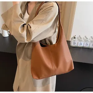 Nahaufnahme der karamellbraunen Ledertasche mit vertikalen Nähten und Lychee-Prägung