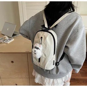 Mini zaino in nylon bianco crema indossato da una modella con ciondolo a forma di cane