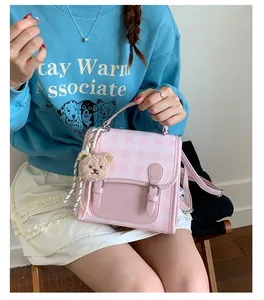 Detail of pink plaid mini backpack with a teddy bear charm and push-lock closure
