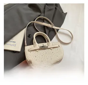 Detail of cream saddle bag with silver studs, top handle and metal clasp closure