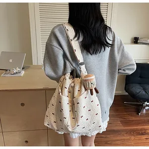 Detail of white mesh shoulder bag with red bow prints and plush pendant in office setting