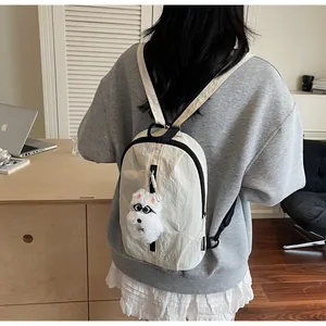 Dettaglio zaino in nylon beige con charm a forma di cucciolo e chiusure lampo nere a contrasto