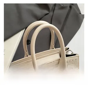 Detailed view of cream saddle bag with rhinestone studs and silver twist lock