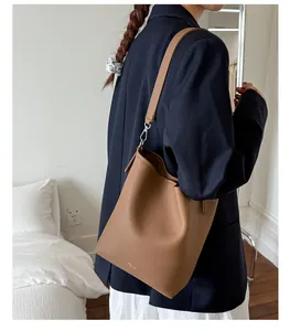 Detail of brown litchi pattern leather bucket bag with silver hardware and adjustable strap