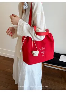 Detail of red canvas tote bag with drawstring closure and white letter embroidery