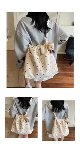 Detail of beige mesh tote bag with red bow embroidery and cupcake plush pendant