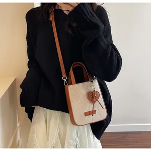 Detail of a vintage mini canvas crossbody bag with leather trim and heart charm