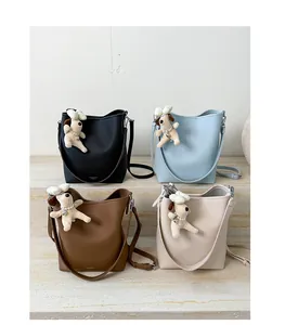 Detail of minimalist bucket bags in four colors with cute puppy charms on stone steps