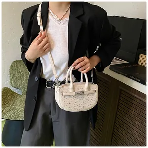 Close-up of beige saddle bag with sparkling rhinestones and silver metallic twist lock