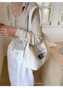 Close-up of cream canvas tote bag with blue drawstring and elegant cursive lettering