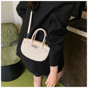 Detail of beige saddle bag with silver twist lock and sparkling rhinestone studs