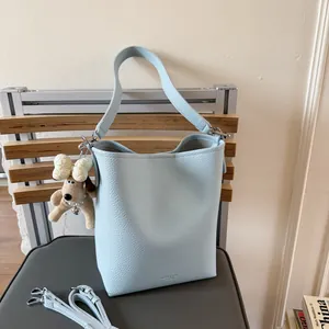 Chic light blue lychee pattern bucket bag with cute plush puppy charm and shoulder strap
