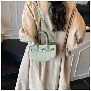 Detail of light green woven saddle bag with rhinestones worn by a model in a trench coat