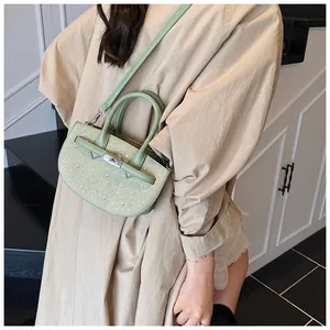 Detail of light green woven saddle bag with sparkling rhinestone accents and silver lock