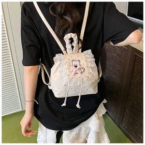 Detail of cream backpack with black dots, lace trim, and cute bear embroidery on a model