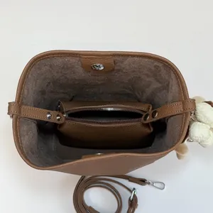 Brown leather bucket bag with inner pouch and plush charm shown from a top-down view