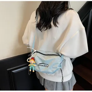 Light blue nylon crossbody bag with black logo and cute doll charm worn by model