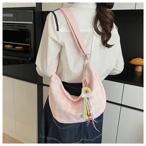 Détail d'un sac bandoulière rose à carreaux avec broderie love et pendentif arc-en-ciel
