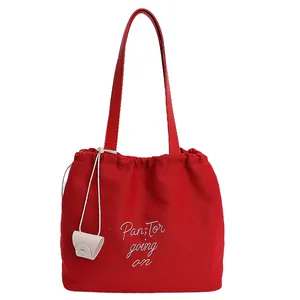 Red canvas tote bag with drawstring closure, letter embroidery and mini pouch accessory