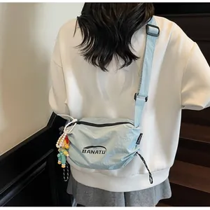 Light blue crossbody bag with BANATU logo and cartoon pendant shown on a model back