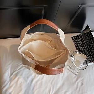 Canvas tote bag with leather handles showing internal compartments and laptop storage