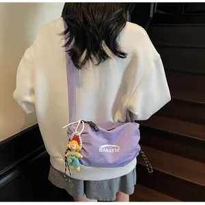 Detail of purple nylon dumpling bag with adjustable strap and cute doll pendant accessory