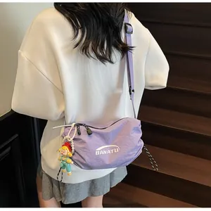 Detail of light purple canvas crossbody bag with BANATU logo and cute doll pendant