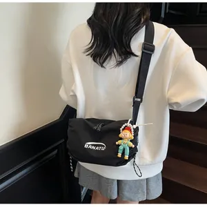 Detail of black nylon crossbody bag with BANATU logo and colorful cartoon charm