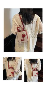 Detail of canvas tote bag with red leather trim and heart charm on a textured strap