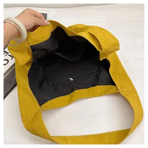 Interior view of yellow canvas tote showing black lining with zipper and open pockets