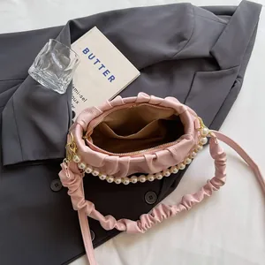 Rosa plissierte Wolken-Handtasche mit Perlenkette und weichem Leder auf grauem Anzug