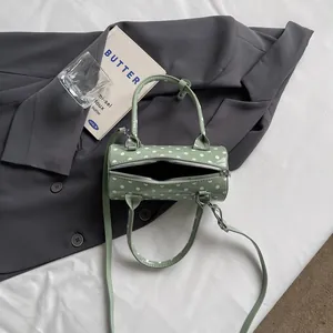 Stylish green polka dot cylinder handbag with top handles and shoulder strap