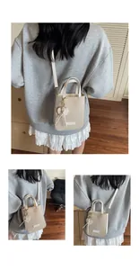 Detailed view of cream canvas mini tote bag with white faux leather trim and heart charm