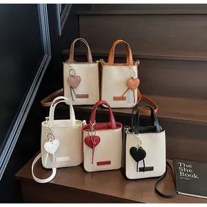 Detailed group view of five canvas mini tote bags with colorful leather trim and heart charms