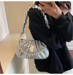 Nahaufnahme einer silbernen Falten-Cloud-Tasche mit eleganten weißen Perlenketten-Details
