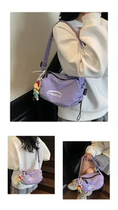Detail of purple nylon crossbody bag with logo branding and adjustable strap