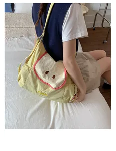 Detalle del lindo bolso bandolera de lona amarilla con forma de manzana y bordado rojo