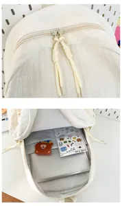 Détail du sac à dos blanc cassé montrant le tissu texturé et la double fermeture éclair