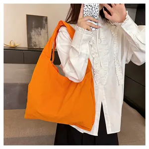 Detail of a bright orange canvas tote bag showing soft fabric texture and slouchy design