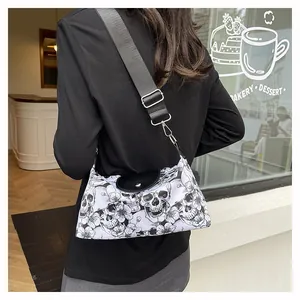 Borsa a tracolla bianca con teschi e fiori e cinturino nero indossata da una modella