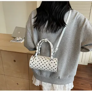 Rear view of a white cylindrical polka dot handbag with silver metal hardware detail