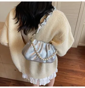 Detail der silbernen Cloud Bag mit Perlenkette und Metallic-Finish am Model gezeigt