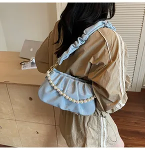 Detailansicht hellblaue gefaltete Cloud-Tasche mit Perlenkette und glänzendem Finish
