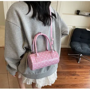 Detailed view of pink polka dot barrel bag worn crossbody by a model in soft lighting