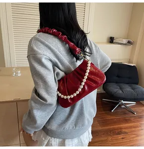Detailaufnahme der roten Cloud-Tasche mit Perlenkette und glänzender Oberfläche